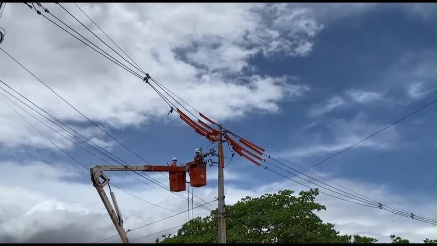 Eletricistas em cesto aéreo executando serviço em rede de média tensão